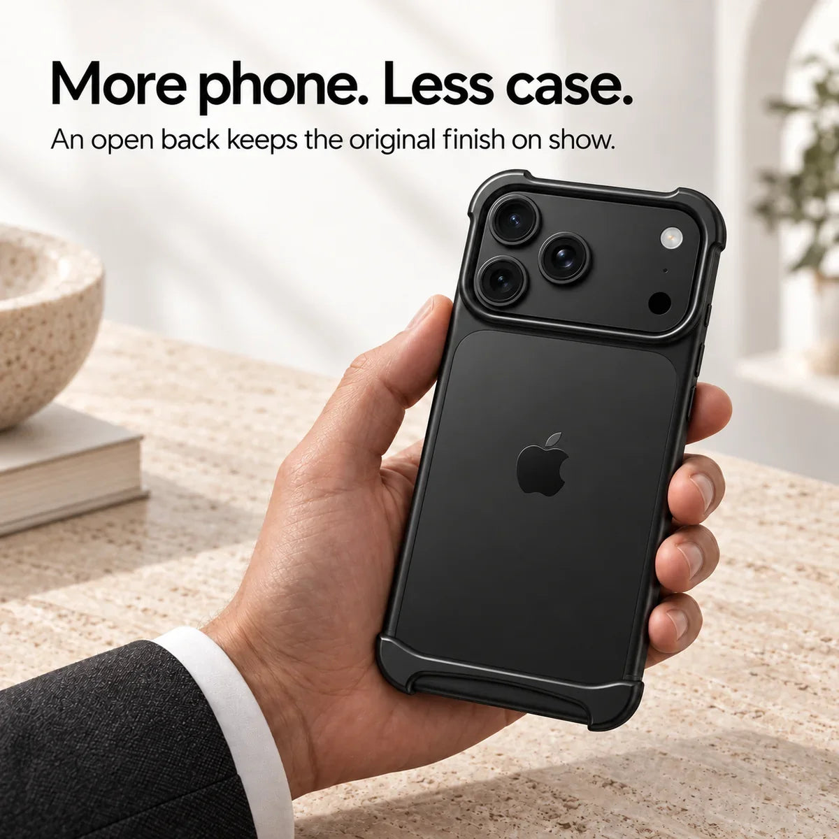 Black metal phone bumper held above a pale stone desk, showing the exposed phone back #color_Midnight Black
