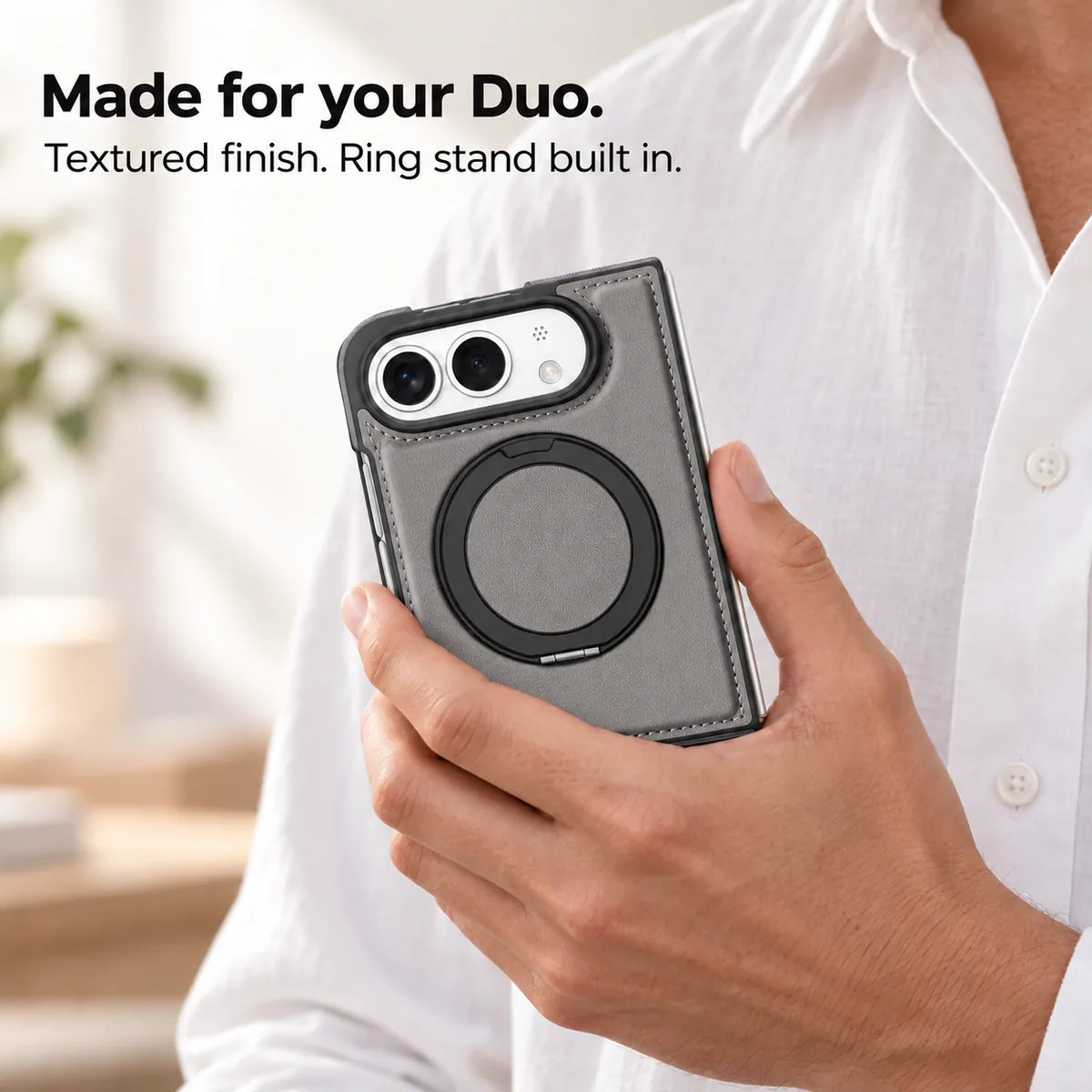 Hand holding a textured synthetic leather folding phone case with the ring stand folded flat. #color_Titanium Gray