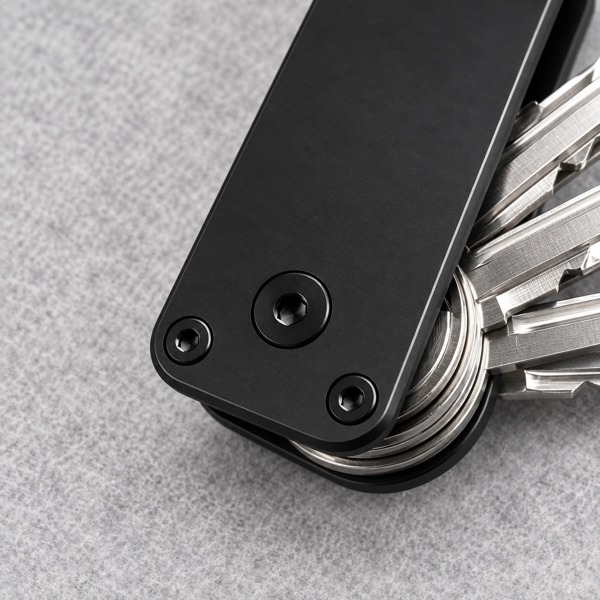 Close-up of the aluminum key organizer's pivot screw, corner screws and stacked keys.