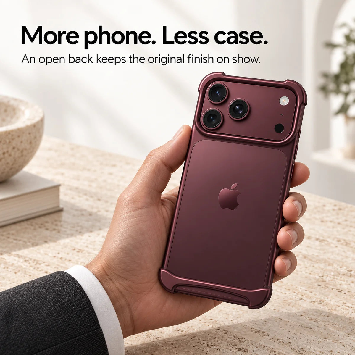 Burgundy metal phone bumper held above a pale stone desk, showing the exposed phone back #color_Burgundy
