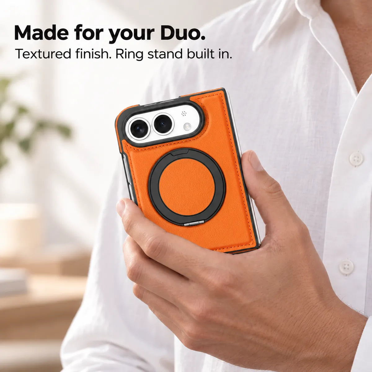 Hand holding a textured synthetic leather folding phone case with the ring stand folded flat. #color_Cosmic Orange