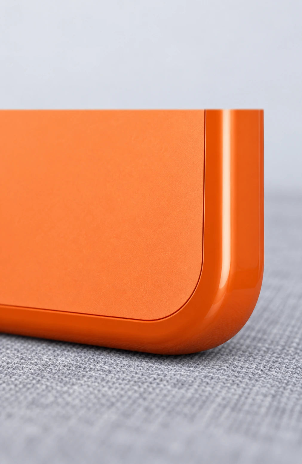 Close-up of the reinforced orange corner where the glossy edge meets the matte back panel.
