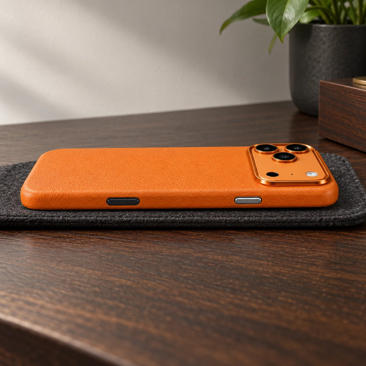 Low side view of an orange vegan leather phone case with its fitted buttons visible.